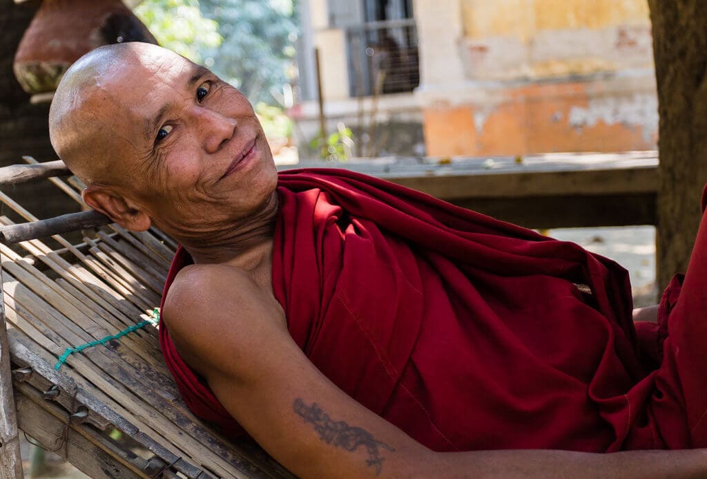 Starý mnich v klášterní zahradě v Mandalayi