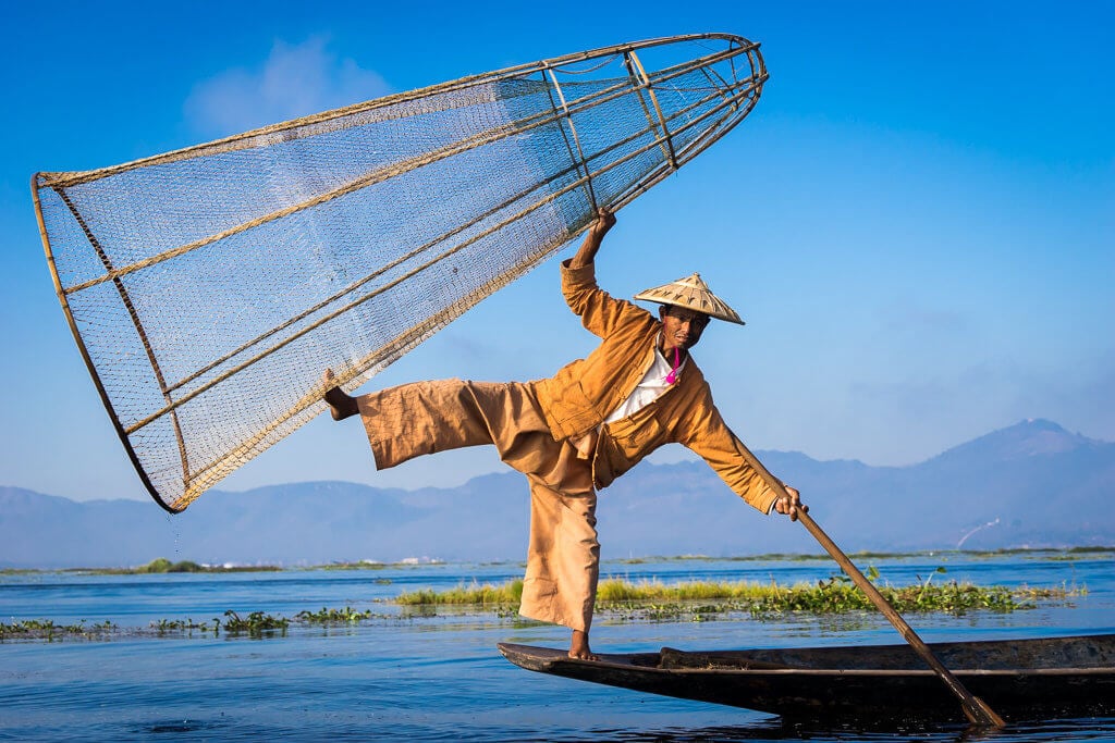 Pózující rybář na jezeře Inle s typickou kůželovitou sítí