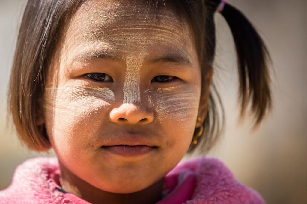 Mladá dívka s thanakou na tváři, kterou Barmánci používají jako orchranu před sluncem