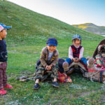 Malé děti kyrgyzských nomádů si hrají na koňských sedlech